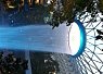 View of tall palm trees and sky seen through a circular rope net with the sun shining from the upper right