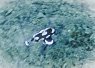 A single clownfish swimming over a sandy seabed with scattered coral fragments