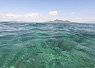 Clear turquoise ocean water with small waves under a partly cloudy sky