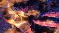 Close-up of glowing embers and logs burning with yellow-orange flames