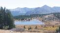 Mountain lake surrounded by autumn shrubs and pine trees with towering rocky peaks in the background