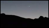 Silhouette of a mountain ridge against a darkening twilight sky with a single bright star or planet visible