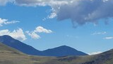 Mountain landscape with a grassy ridge in the foreground and blue sky with scattered clouds above