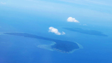 Aerial view of two islands surrounded by blue ocean with a couple of white clouds above
