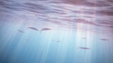 Underwater scene with sunlight filtering through the water surface and a group of small fish swimming near the top
