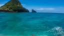 View from a boat of turquoise ocean water with green, rocky islands under a clear blue sky