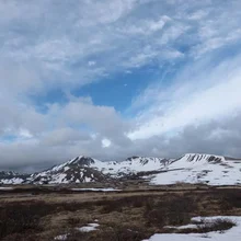 Mountain landscape with patches of snow and cloudy sky with some blue visible